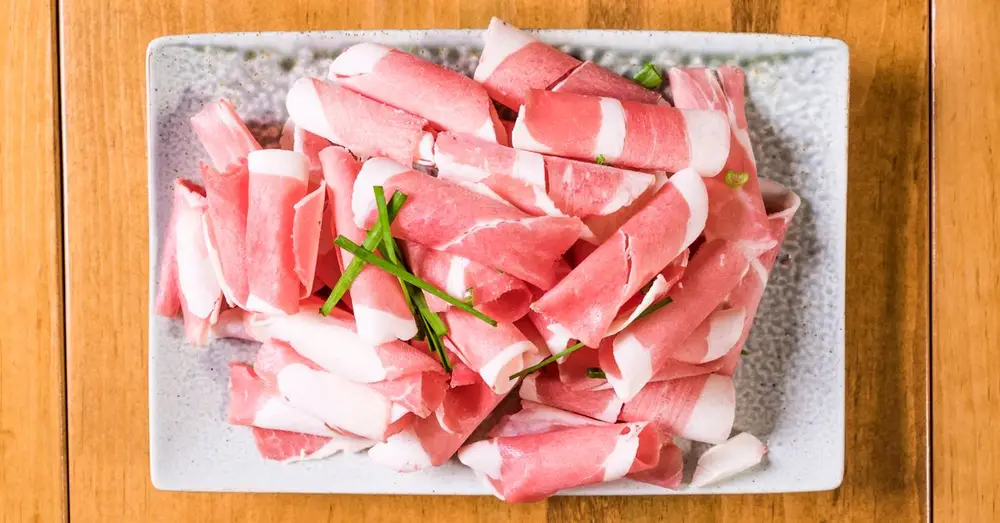 Top view of raw meat strips on a ceramic plate, ideal for food presentations and Korean BBQ concepts.