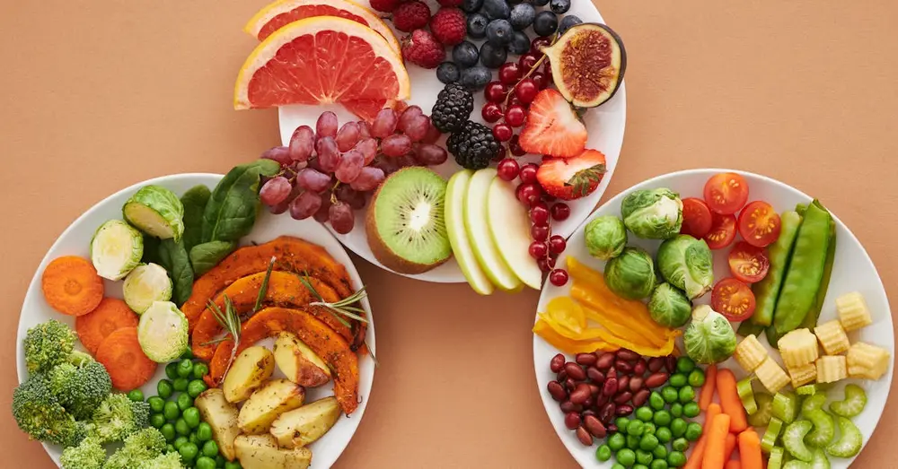 Top view of vibrant plates of fresh fruits and vegetables, perfect for a healthy lifestyle.